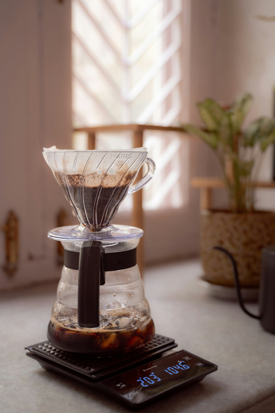 Pour-over brewer and glass carafe centered on a digital coffee scale